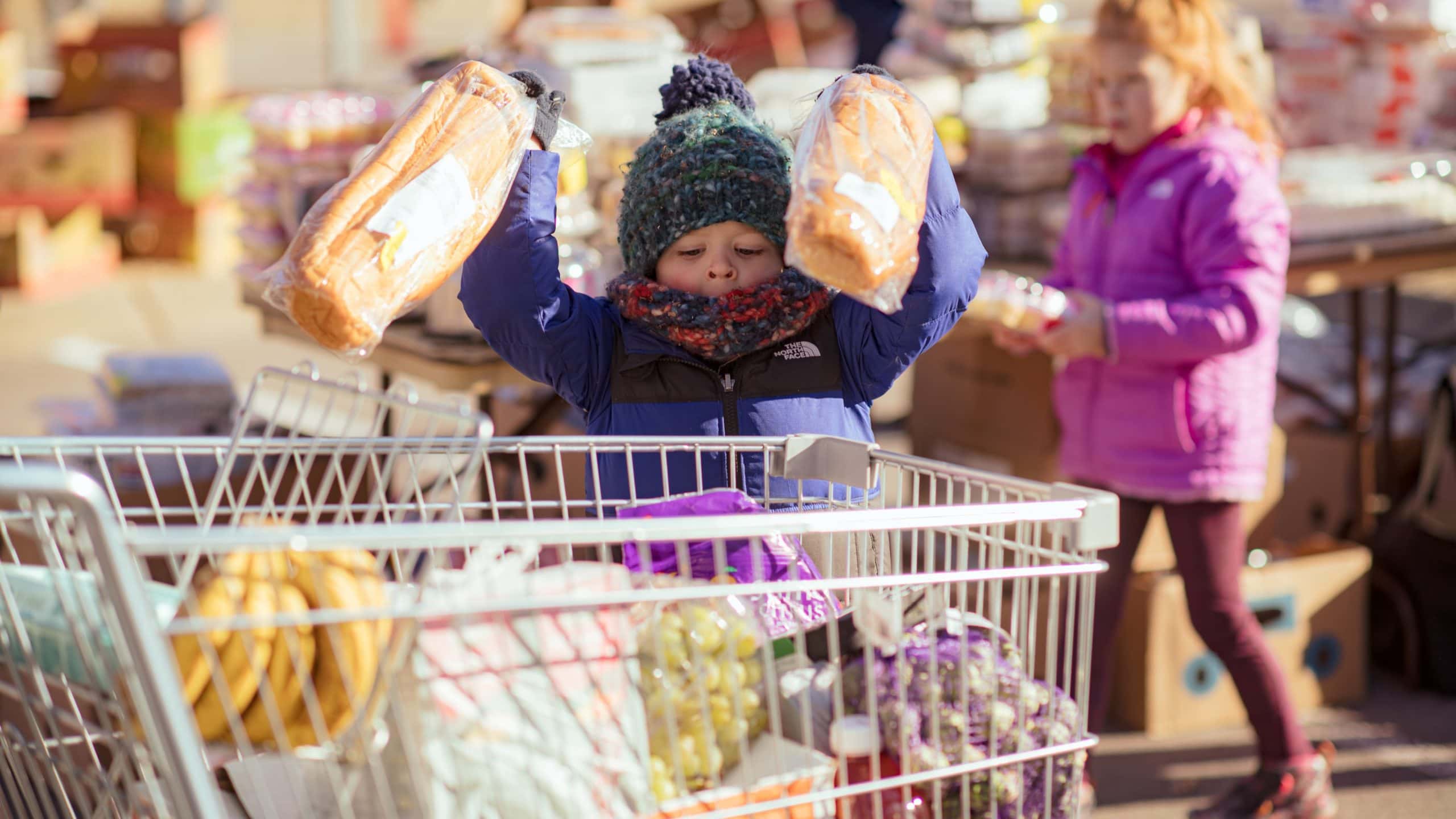 A young volunteer puts bread into a shopping cart at a One Generation Away mobile food pantry distribution in Ashland City Tennessee. Photo credit goes to Kris Orlowski.