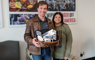 OneGenAway founder and director of development Elaine Whitney stands with volunteer Timothy Myles, who is holding a gift basket of OneGenAway swag