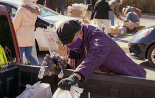 Laura fills the back of a truck with groceries at a OneGenAway mobile food pantry distribution.