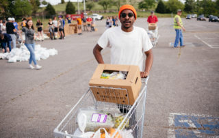 Chuka pushes a cart full of food at OneGenAway's mobile food pantry.