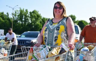 Becky pushes a cart full of food at OneGenAway's mobile food pantry.