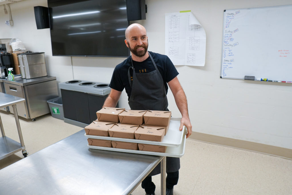 Ben Tyson carries boxed restaurant-inspired meals to the Patchwork fridge.
