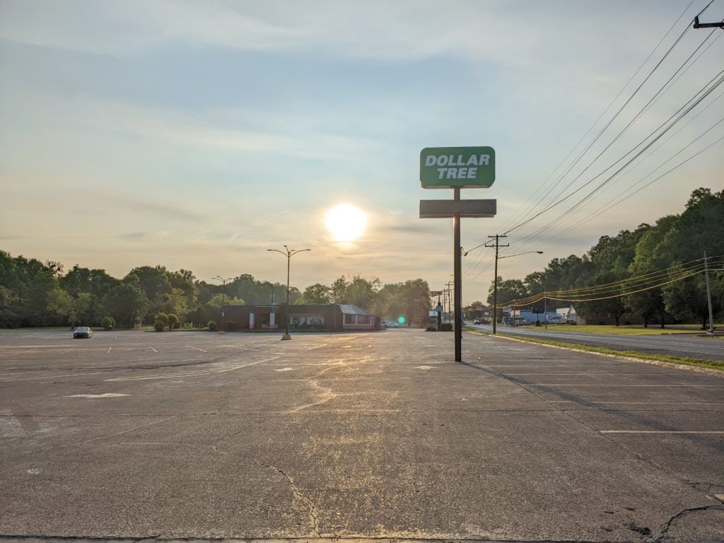 The sun rises behind a Dollar Tree sign in an empty parking lot in Waverly Tennessee